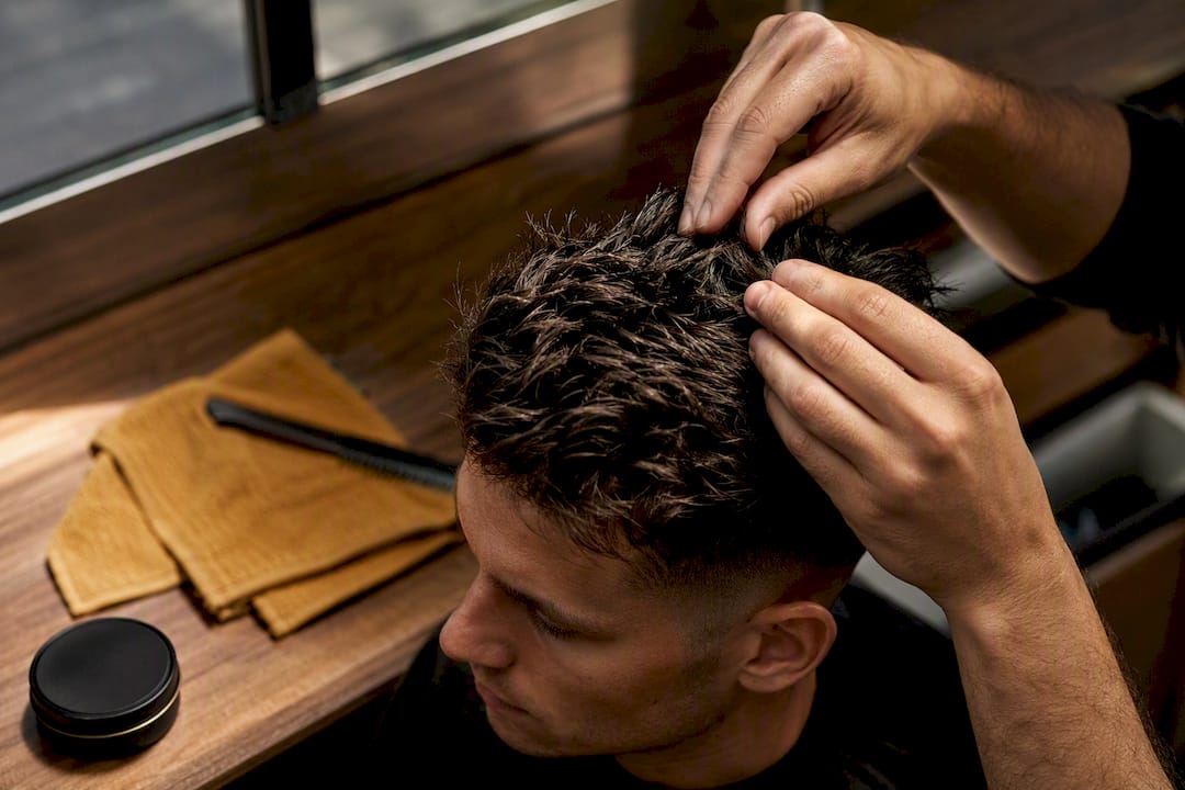 Hands shaping textured hair with clay