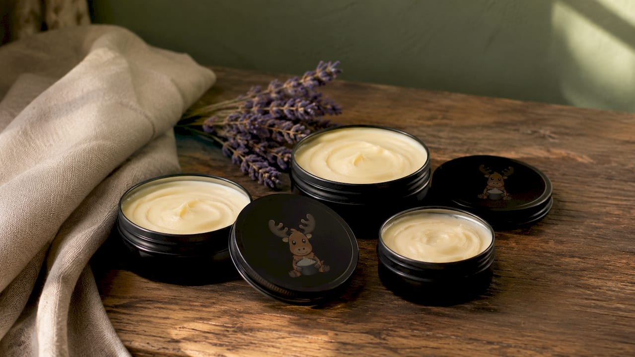 Black matte tins of tallow skincare balms on wood shelf