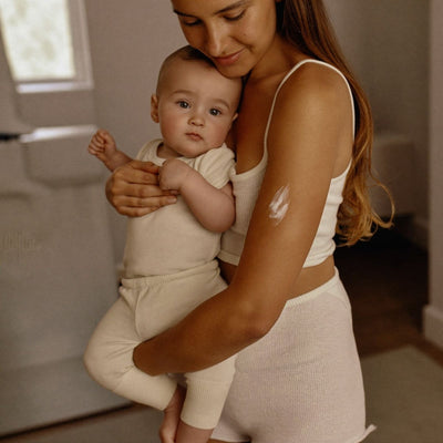 New mom holding her baby with natural tallow balm on her arm — Moose's Tallow new mom skincare gifts